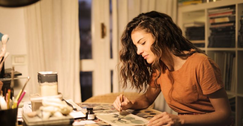 Concentration - Young woman painting on paper at workplace