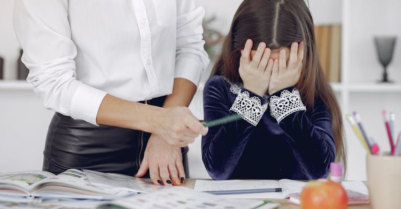 Study Mistakes - Upset little girl sitting near crop woman in classroom