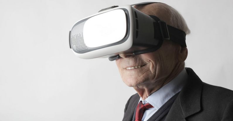 Simulations - Smiling elderly gentleman wearing classy suit experiencing virtual reality while using modern headset on white background