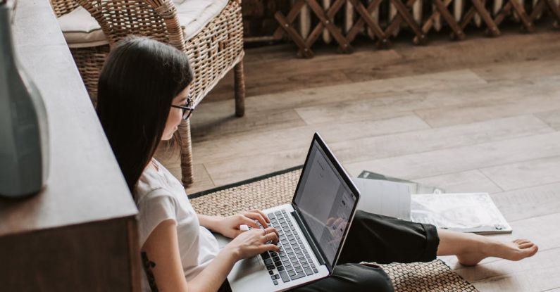 Mentorship Programs - Young barefoot woman using laptop on floor near books in stylish living room