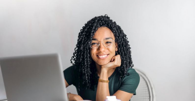 Study Space - Happy ethnic woman sitting at table with laptop