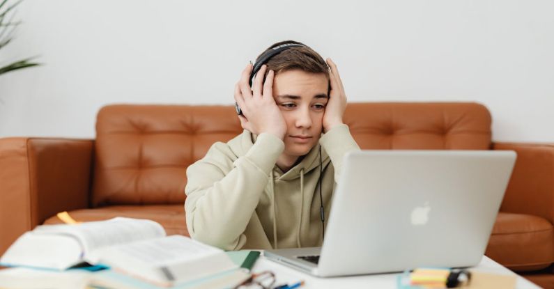 Used Textbooks - Young Man in Beige Hoodie Looking Problematic While Studying